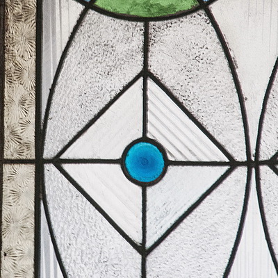 Фрагмент геометического витража, созданного с использованием фактурных цветных и бесцветных стекол. В центре - синяя рюмочная плитка. Петербург, начало ХХ века